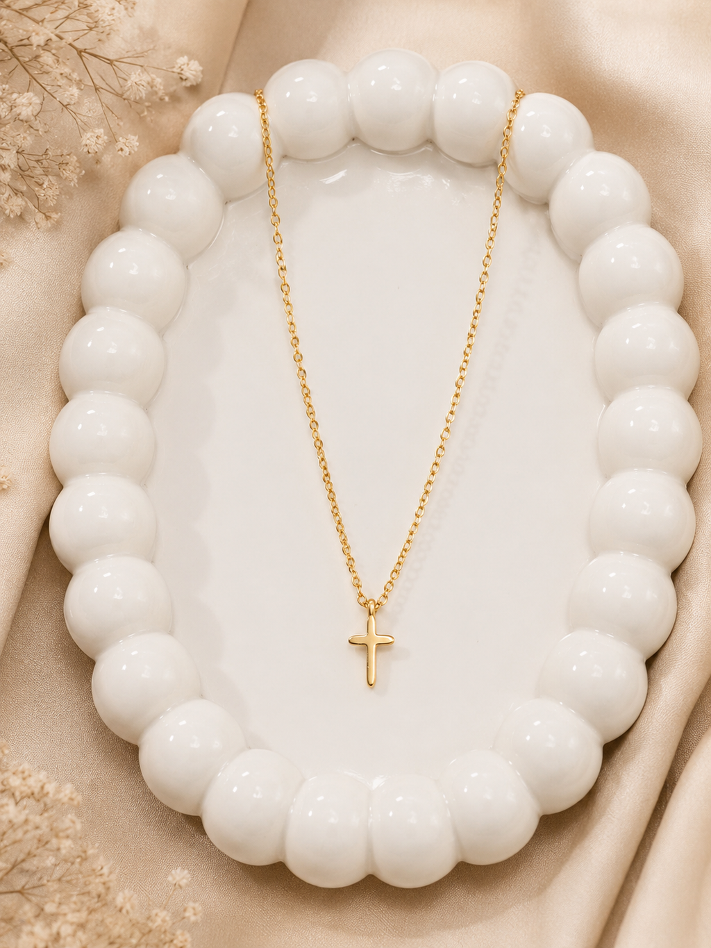 Dainty gold cross pendant necklace on white display tray